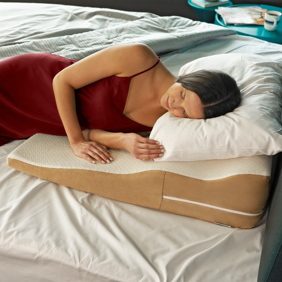 Woman lying on a wedge-shaped pillow on a bed