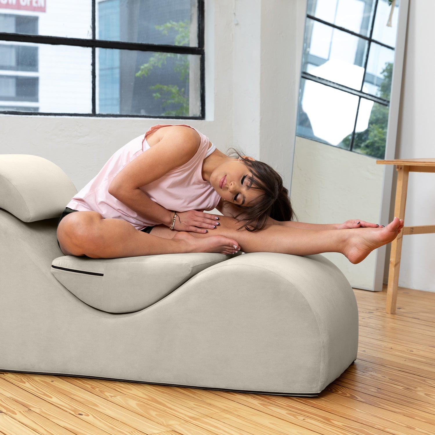 Woman lying on a modern massage chair in a bright room with large windows.