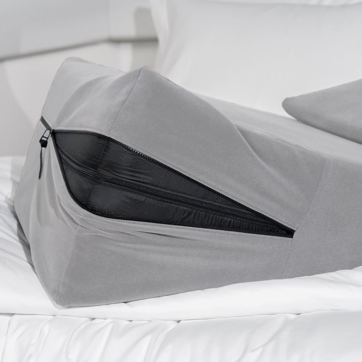 Gray zipped-open ramp pillow on a white mattress