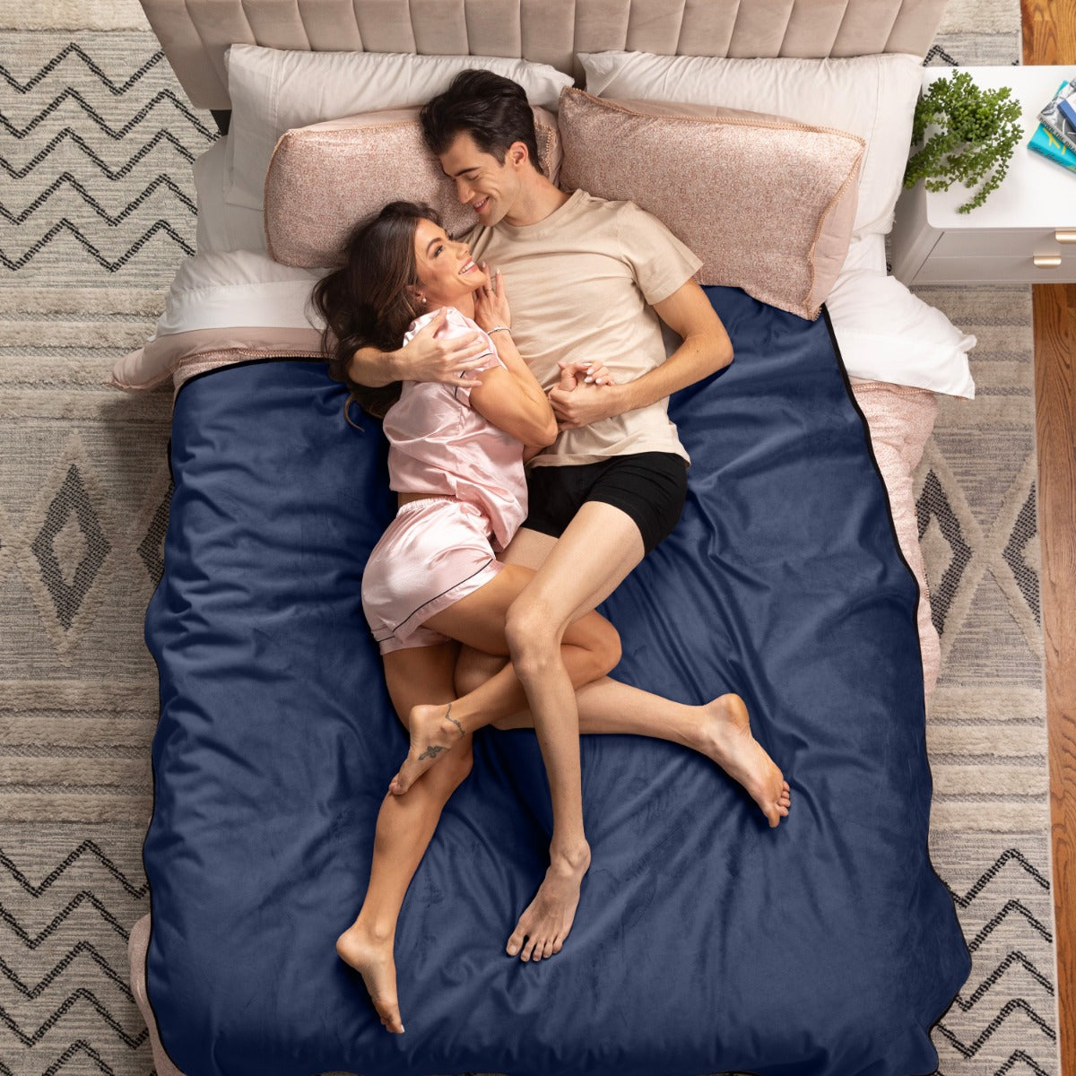 Couple lying on a bed with blue sheets in a bedroom setting