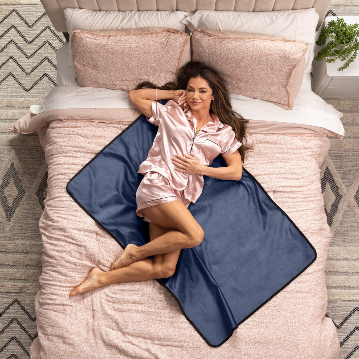 Woman lying on a bed with a blue heating pad under her legs