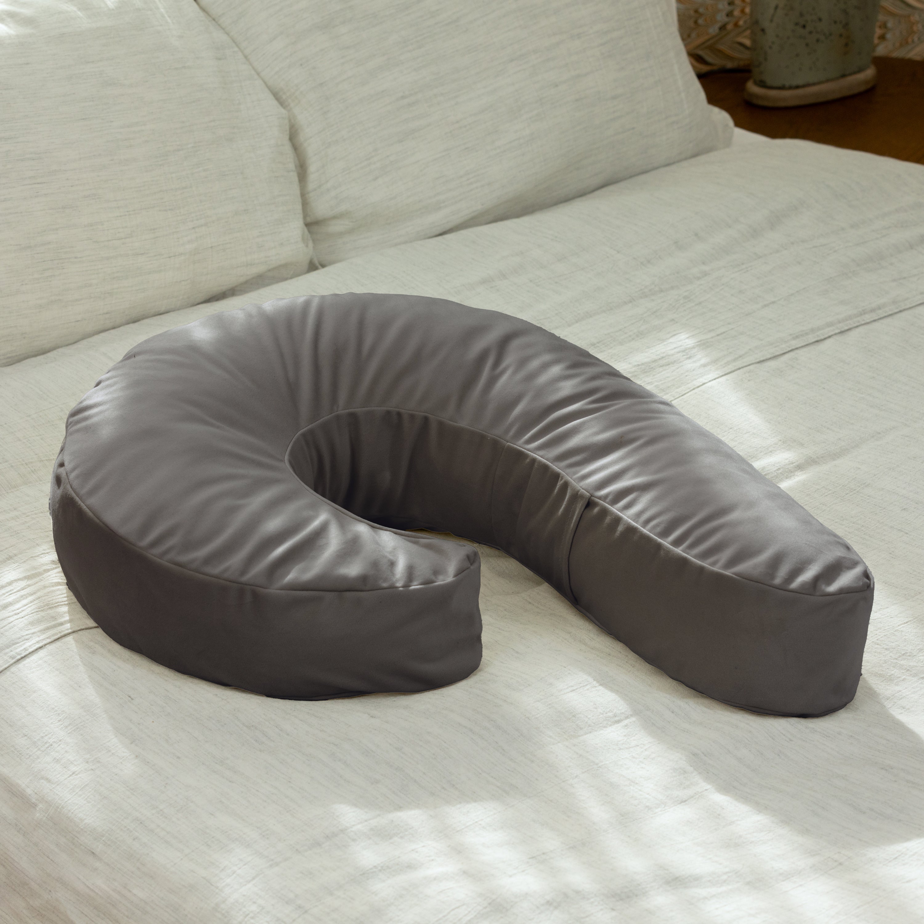 Gray U-shaped pillow on a light-colored couch