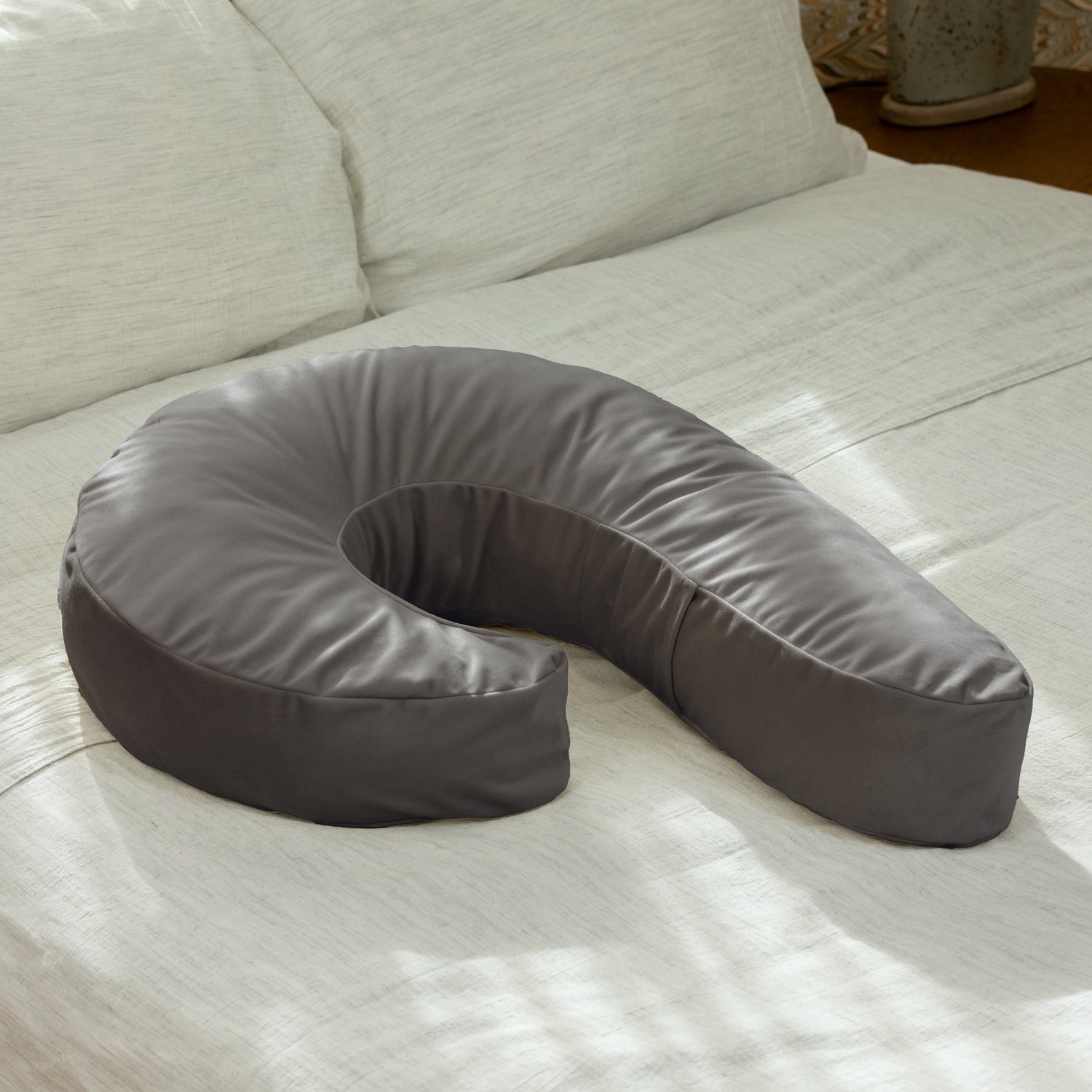 Gray U-shaped pillow on a light-colored couch
