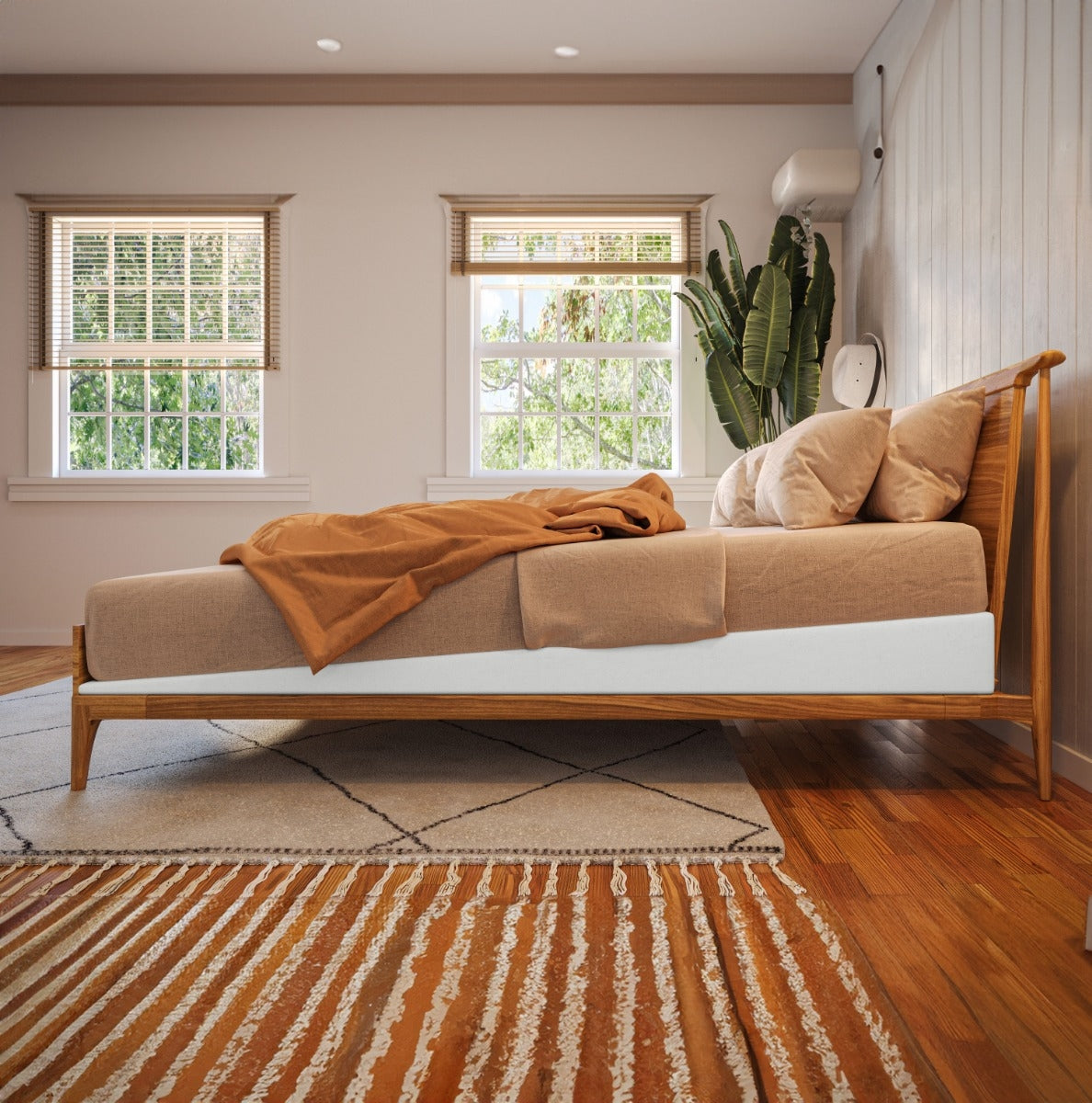 Bedroom with wooden bed, brown bedding, and a plant