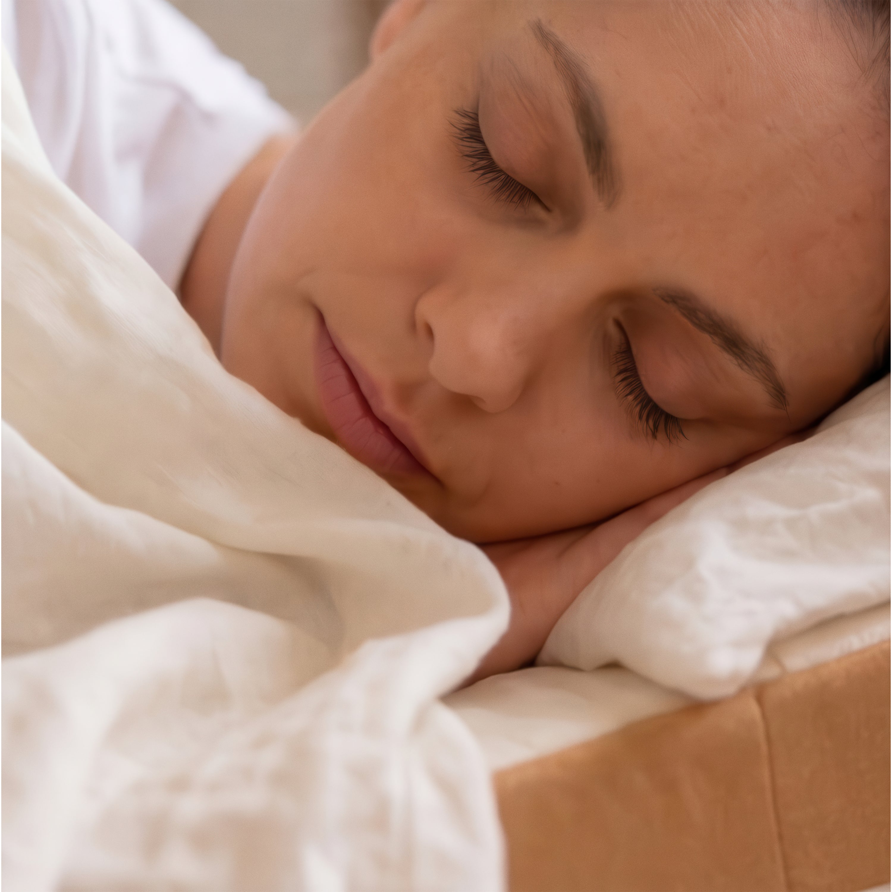 Inclined mattress topper on a bed with neutral bedding
