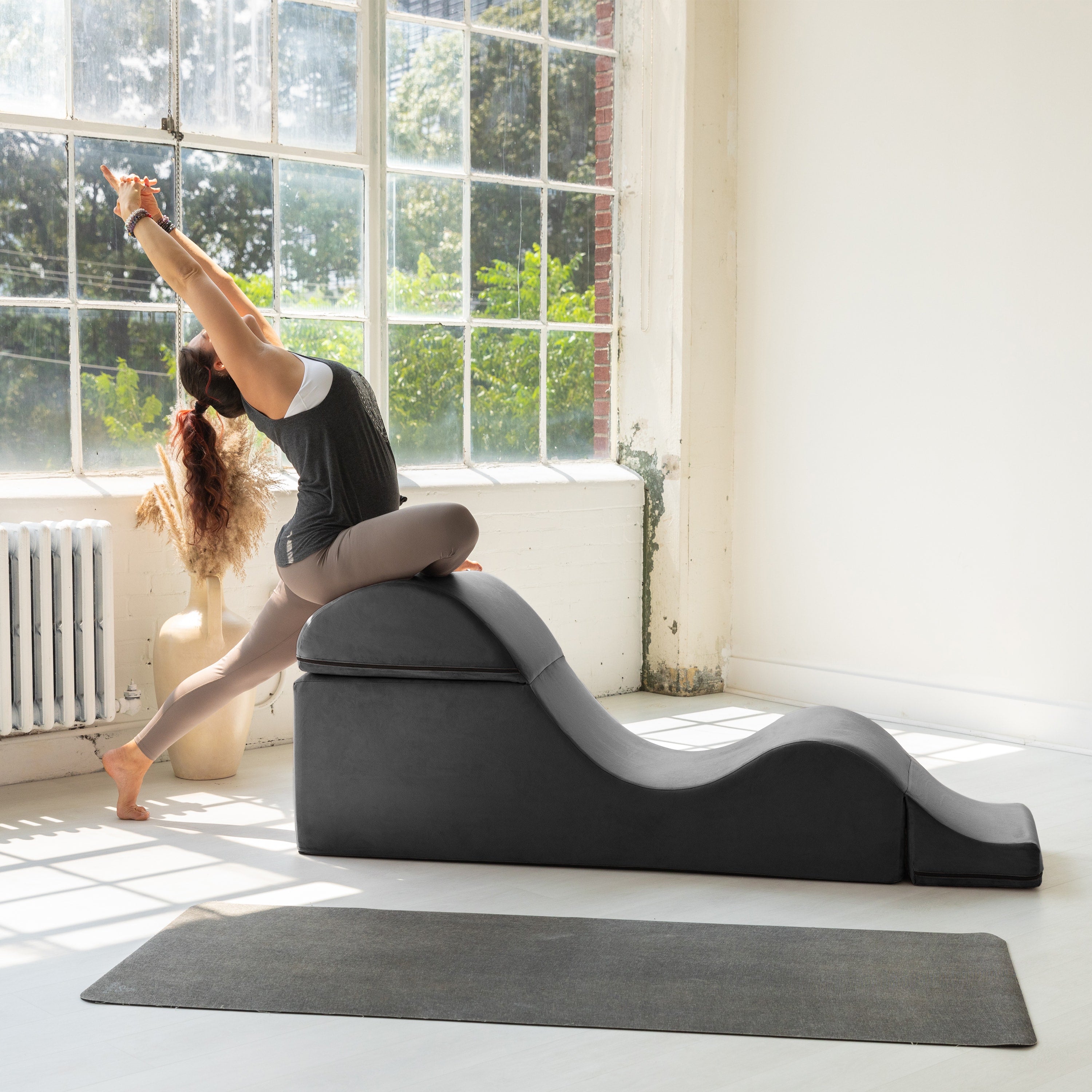 Woman using a yoga wedge in a bright room with large windows