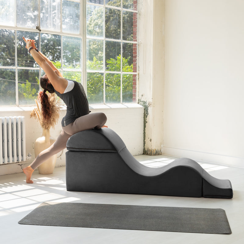 Woman using a yoga wedge in a bright room with large windows